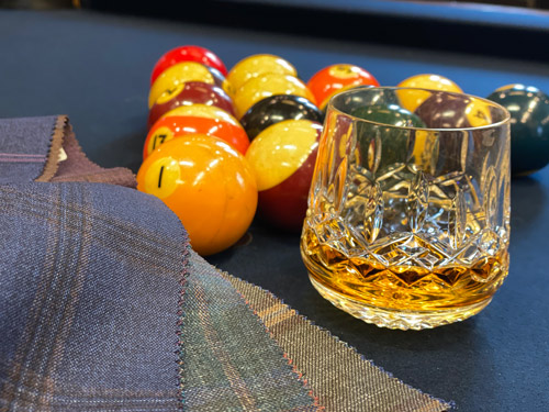 Clothing fabric samples, pool balls and whiskey glass with whiskey. 